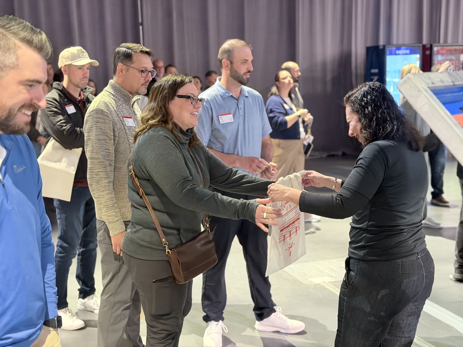 Corporate event attendees receiving branded t-shirts and merchandise at a professional vendor booth